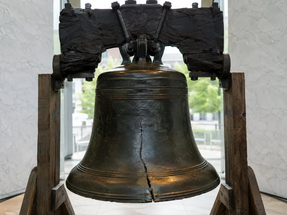 The Liberty Bell hanging from its wooden yoke, lit by daylight